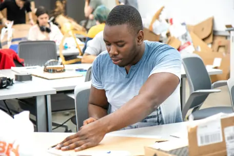 black male student sits at table in art class